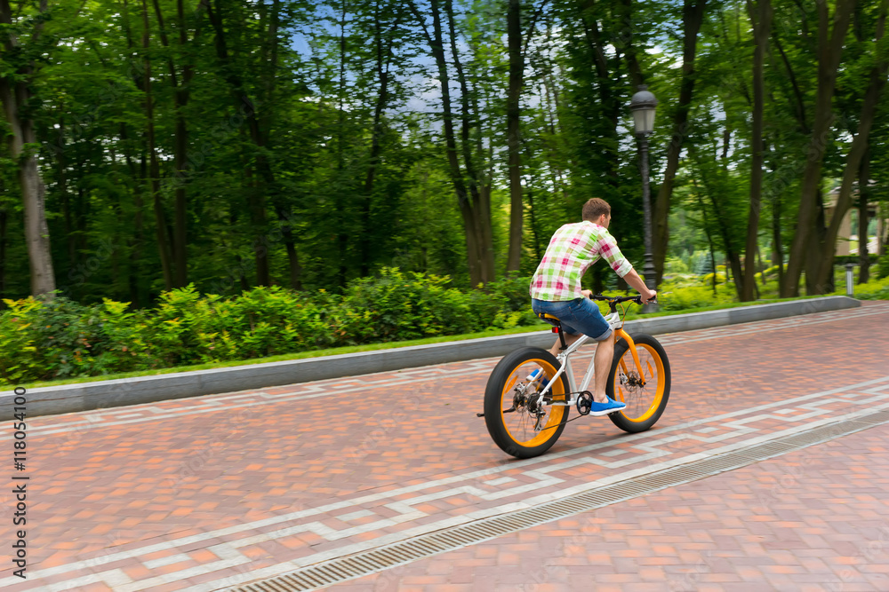 Male riding a bike on a footpath in a park
