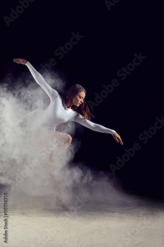 Ballerina dancing with flour on a black background. Dancer in a white bathing suit dancing gracefully with flour. Powder Photo Shoot.