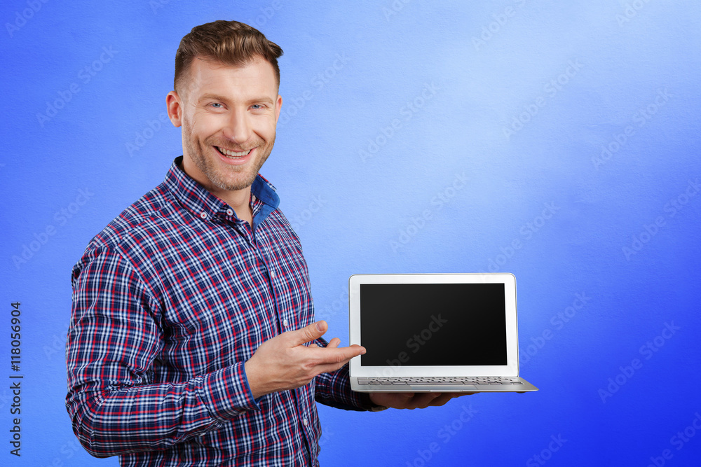 Young man standing, holding laptop computer, working. Young man standing, holding laptop computer, working.