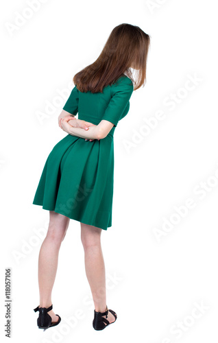 back view of standing young beautiful woman. girl watching. Rear view people collection. backside view of person. Slim brunette interest looking down in green short dress. 