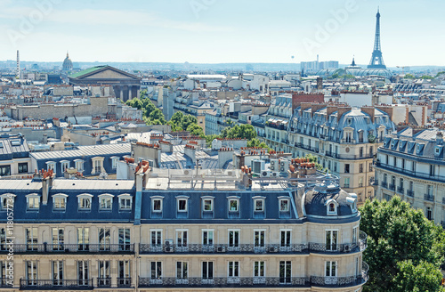 Paris view of the Eiffel Tower above the rooftops. Panorama parisian cityscape aerial view with rooftops, mansards and chimneys.