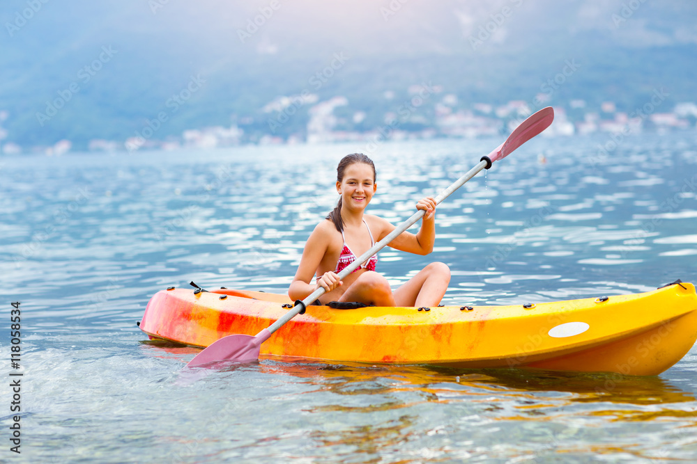 Girl enjoying paddling in kayak on the sea water 