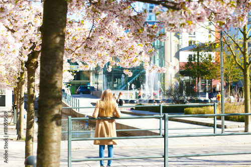 Woman leans on the handrails standing in the blooming park photo