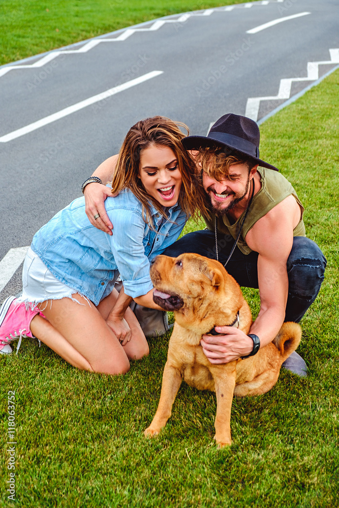 Couple playing with shar pei on the grass Couple playing with shar pei on the grass
