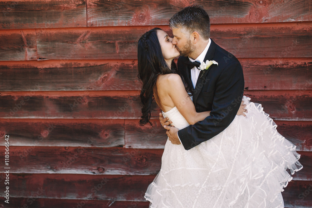 Bride envelopes groom in her curly dress while he kisses her ten