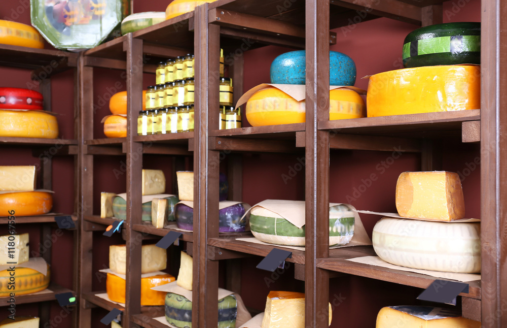 Different kinds of cheese on shelves in cellar