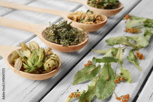 Natural flower and herb selection in wooden spoons on wooden background