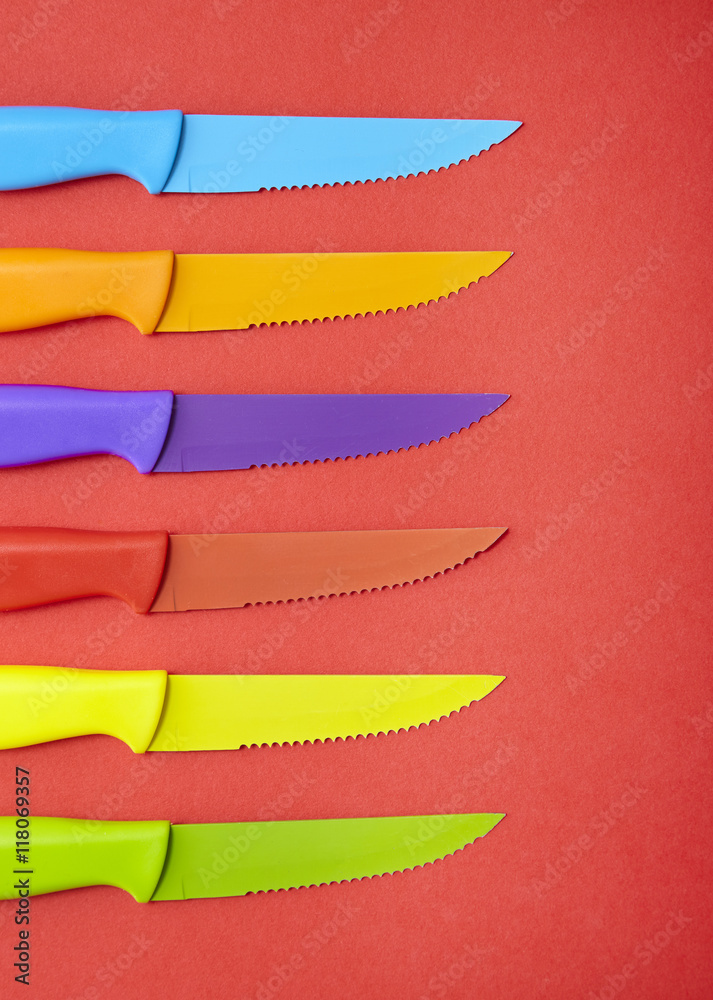 Obraz premium Colorful steak knives on a red background 