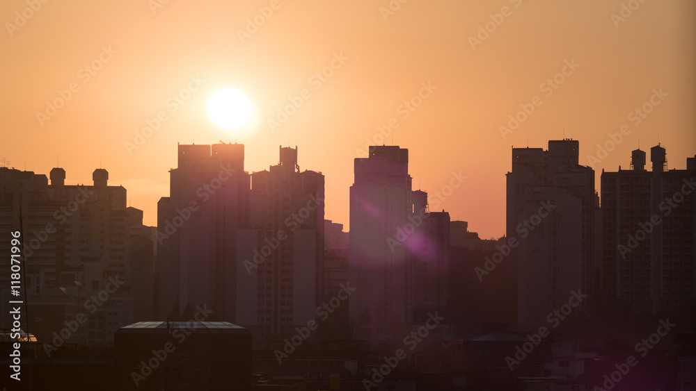 Cityscape in early morning. Building outlines against the warm orange sky and the bright sunshine. Seoul, South Korea