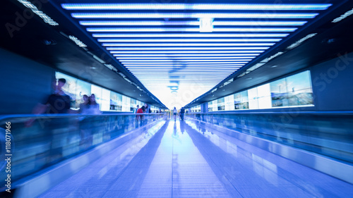 People going in walkway and riding flat escalators at the airport of Seoul, South Korea. Futuristic blue toned shot