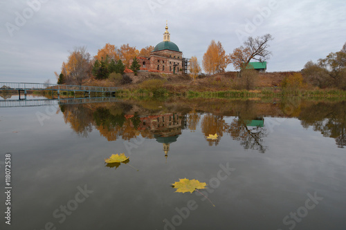 Осенний пейзаж с видом православного храма на берегу озера и желтых листьев