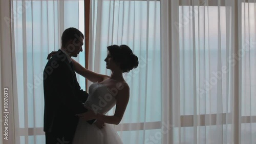 Silhouettes of honeymooners standing next to the window