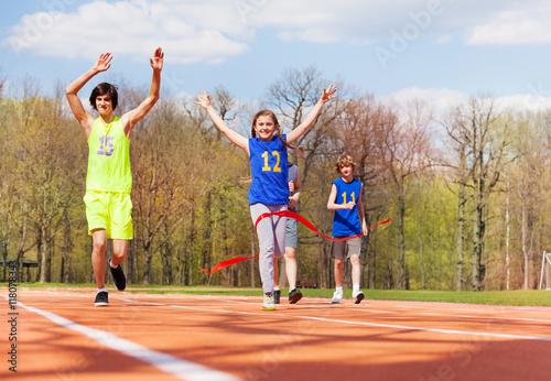 Happy teenage girl crossing finish line in race