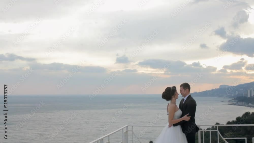 Happy lovers standing on the balcony overlooking the sea and kissing Happy lovers standing on the balcony overlooking the sea and kissing
