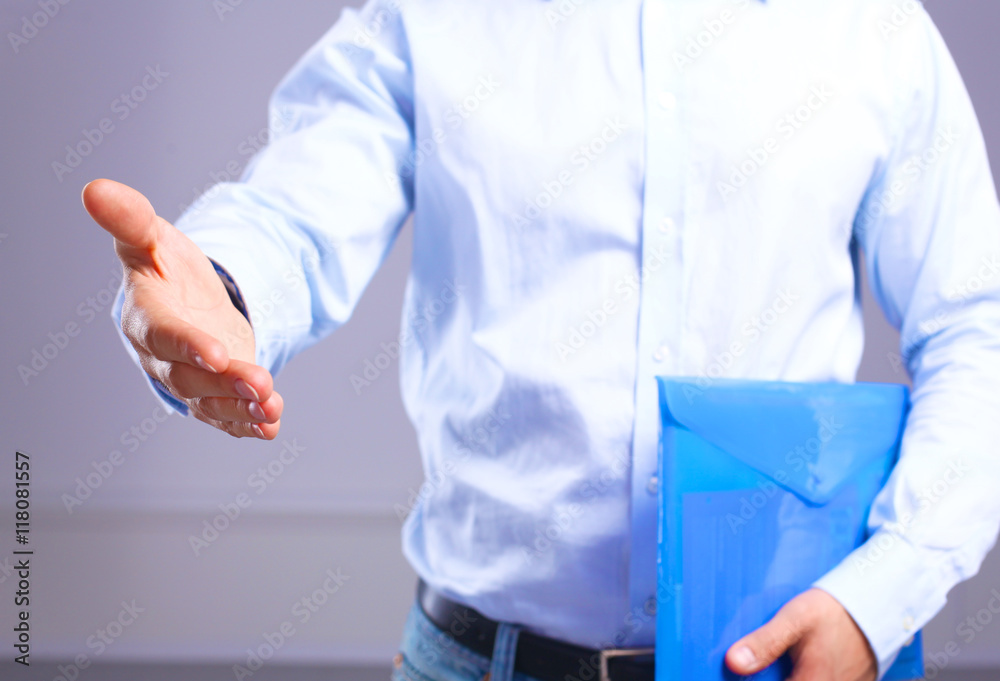 businessman with papers holds out his hand for a handshake