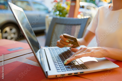 Fototapeta Naklejka Na Ścianę i Meble -  Girl with a laptop in a cafe, shop with a credit card