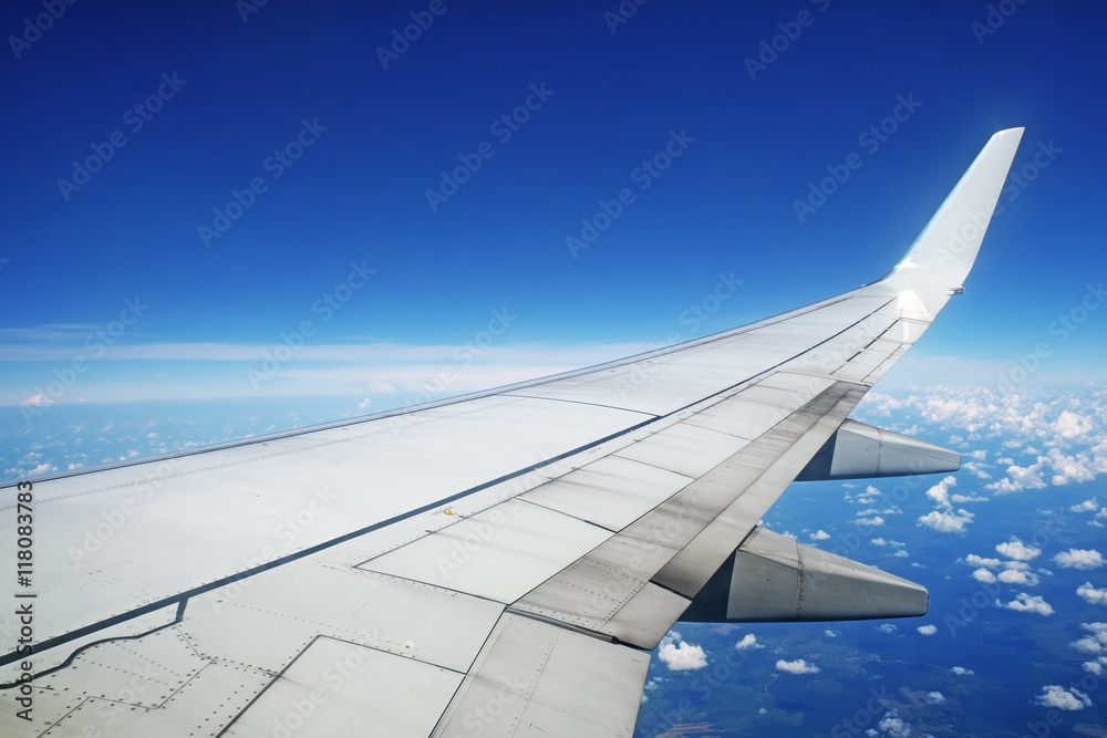 Aircraft wing in flight on blue sky background