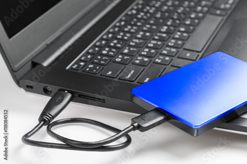 Data transfer from personal black laptop computer to blue external hard disk for backup files and important information using USB connection
