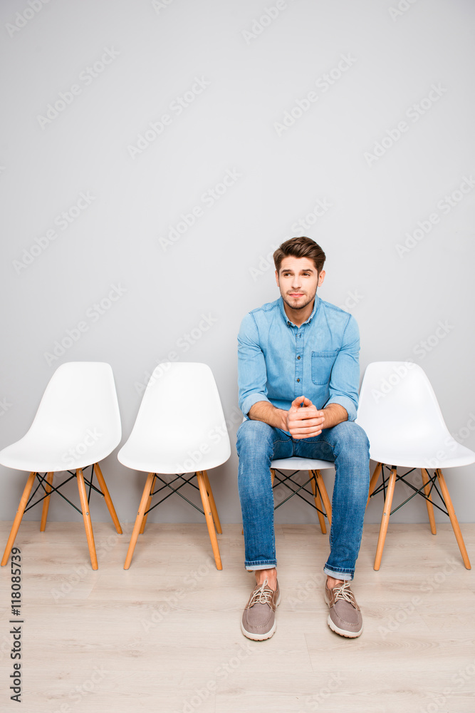 Young handsome man sitting on chair and waiting for his turn