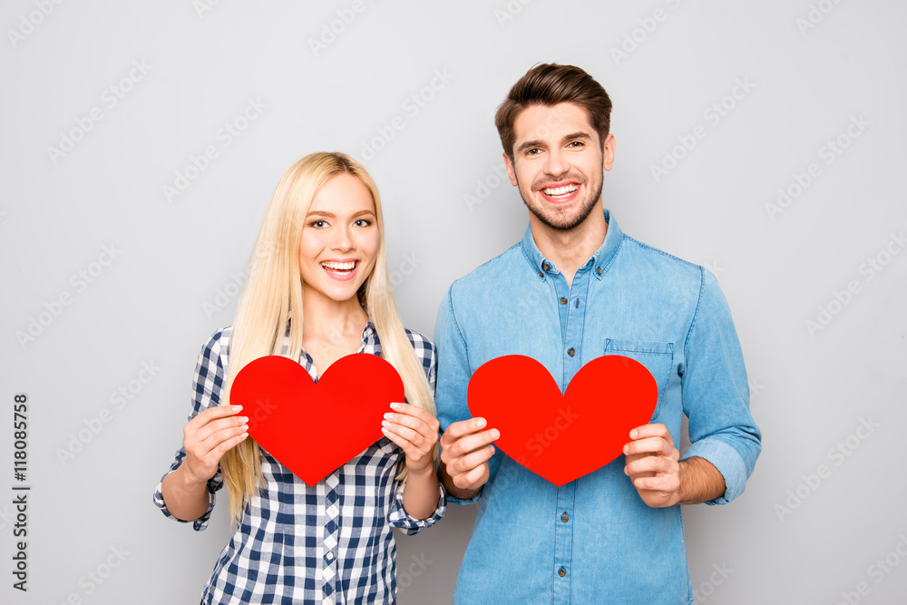 Portrait of smiling man and woman holding two red paper hearts Portrait of smiling man and woman holding two red paper hearts