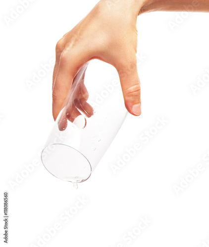 Drop of water falling from empty drinking glass in woman's hand
