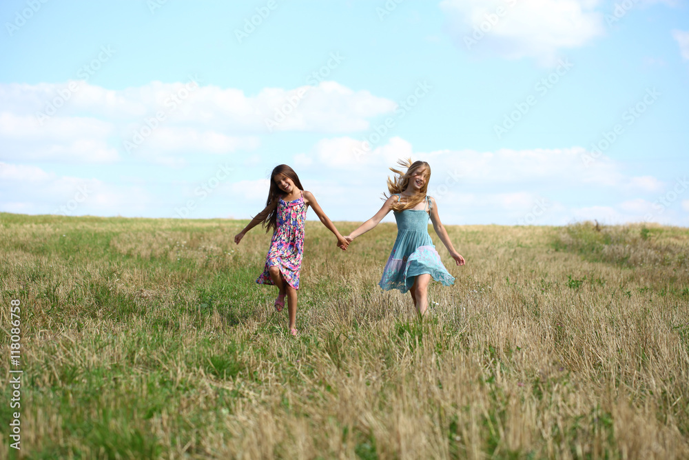 Two little girls running in summer field