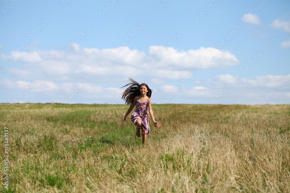 Beautiful young little girl running summer field
