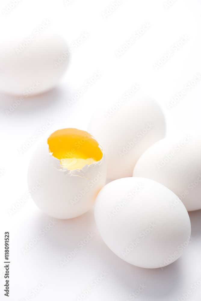 five fresh, free range, white, organic eggs. one broken with selective focus, close up, isolated on white background and vertical five fresh, free range, white, organic eggs. one broken with selective focus, close up, isolated on white background and vertical
