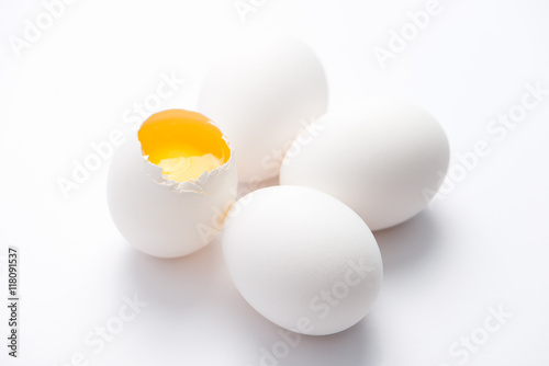 four fresh, free range, white, organic eggs. one broken with selective focus, close up, isolated on white background and horizontal