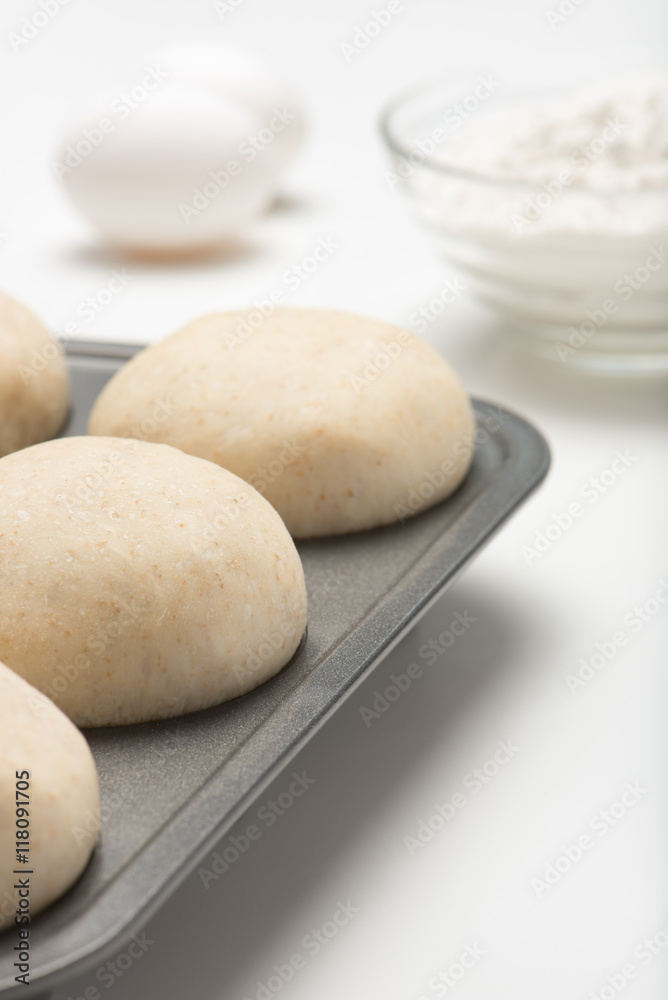 freshly prepared, homemade, uncooked dough balls in a cooking pan with white flour and eggs. isolated, close up, vertical