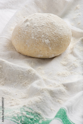 fresh, uncooked pizza or bread dough ball on a white kitchen cloth