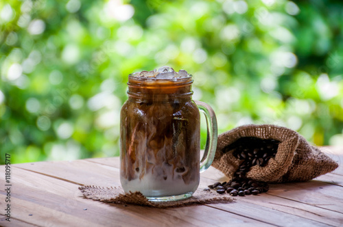 Ice coffee on wooden table with sack of coffee neans photo