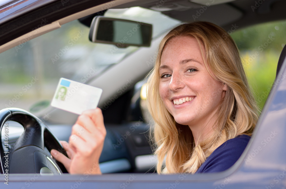 Happy young woman showing off her drivers license