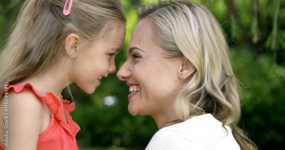 Portrait of cute mother and daughter embracing and smiling in the garden Portrait of cute mother and daughter embracing and smiling in the garden