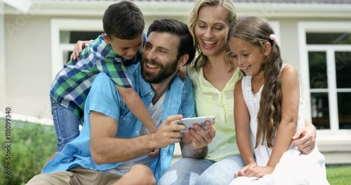 Wallpaper Mural Happy family looking a smartphone in the garden Torontodigital.ca