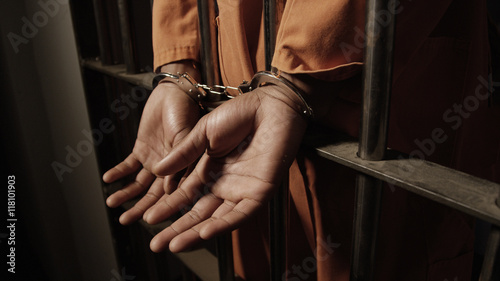 African man in prison - hand cuffed through the bars of his jail cell