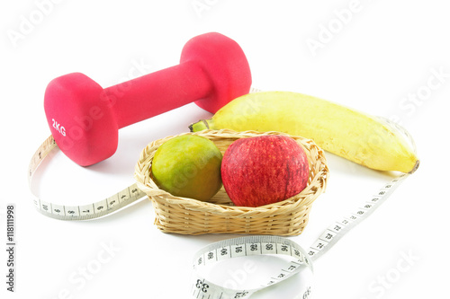 Fitness dumbbells and fruits. Fresh red tasty apple,orange and banana with measuring tape isolated on white