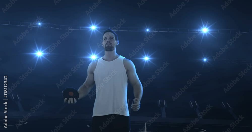 Sportsman is preparing to do discus throw against flashing lights