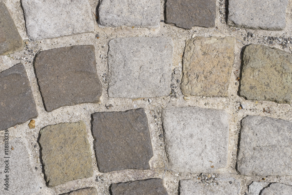 Fototapeta premium Cobble stones in concrete on a path, background texture macro, selective focus