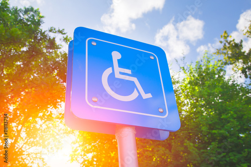 Parking for disability persons sign with green and sun light background.