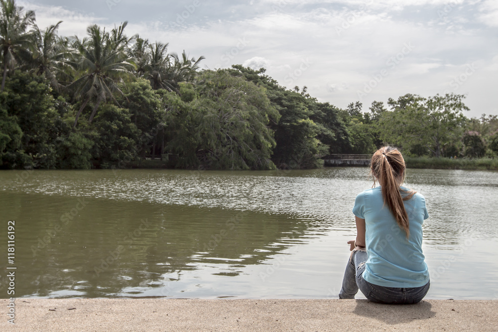 Young Asian woman sits at Lake.