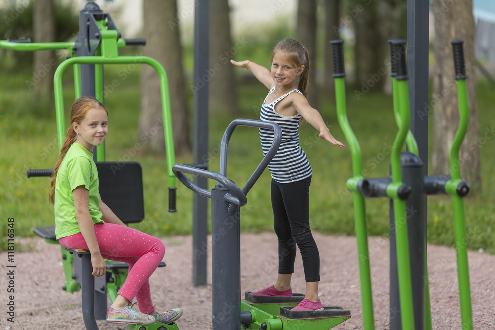 Two little cute girls warming up on the Playground in the Park. Healthy lifestyle.. Two little cute girls warming up on the Playground in the Park. Healthy lifestyle..