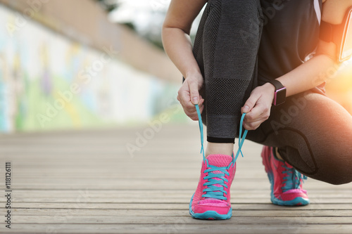 Woman runner tying laces before training. Marathon.