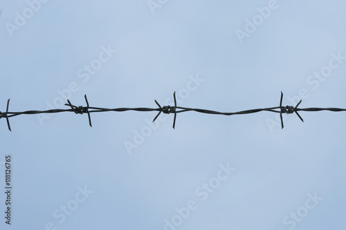 Barb wire fence with blue sky background.