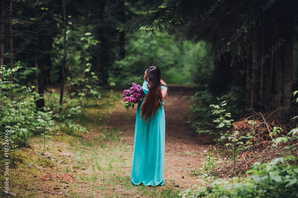 Portrait of a beautiful brunet pregnant girl in a green dress, dreamy and standing in the forest between the pines. Pregnant woman in the park. Portrait of a beautiful brunet pregnant girl in a green dress, dreamy and standing in the forest between the pines. Pregnant woman in the park.