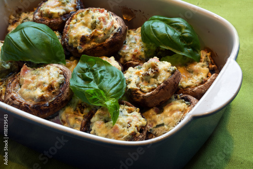 small stuffed champignons baked in a casserole dish with basil garnish