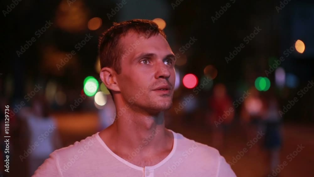 man standing on the street at night. street lights. looking at the big