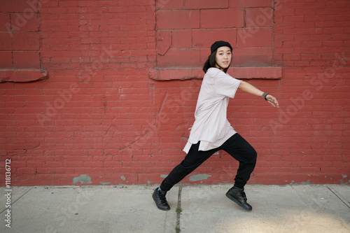 Young Asian woman dancing hip hop in city