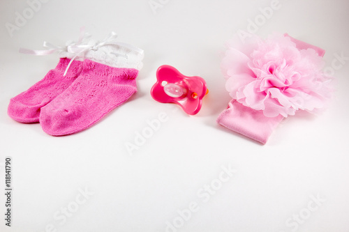 Baby socks, pacifiers and bow on a white background
