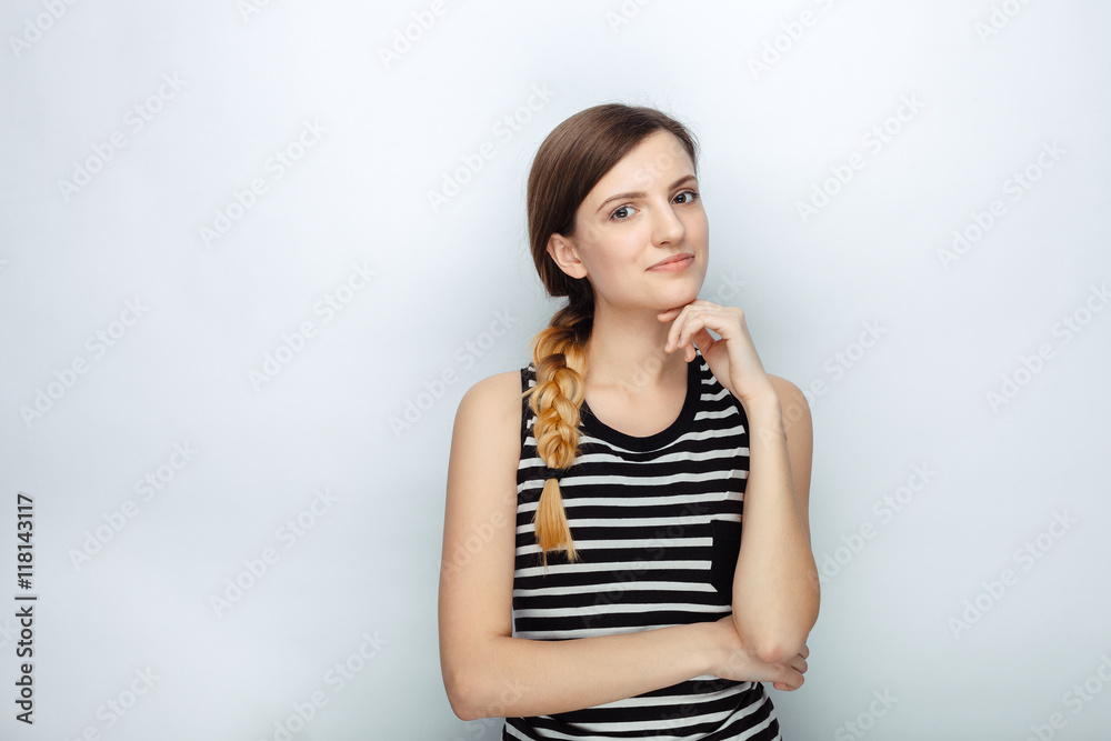 Portrait of happy thoughtful young beautiful woman in striped shirt touching her chin posing for model tests against studio background Portrait of happy thoughtful young beautiful woman in striped shirt touching her chin posing for model tests against studio background
